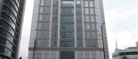 A tall hotel building with a modern glass facade, a prominent sign reading 'CITY TOWER HOTEL,' and a busy street in front.