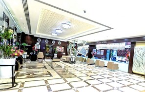 A hotel reception area with a check-in counter, seating area, and decorative plants. - City Tower Hotel (Al-Fujairah)