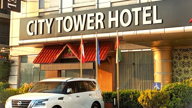 Das Stadthotel City Tower mit einem weißen SUV davor.