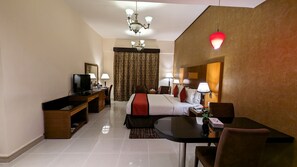 A hotel room with a bed, desk, television, lamps, and a chandelier. - City Tower Hotel (Al-Fujairah)