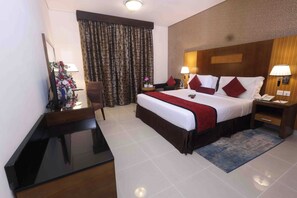 A hotel room with a bed, bedside tables, a desk, a chair, a TV, and curtains.