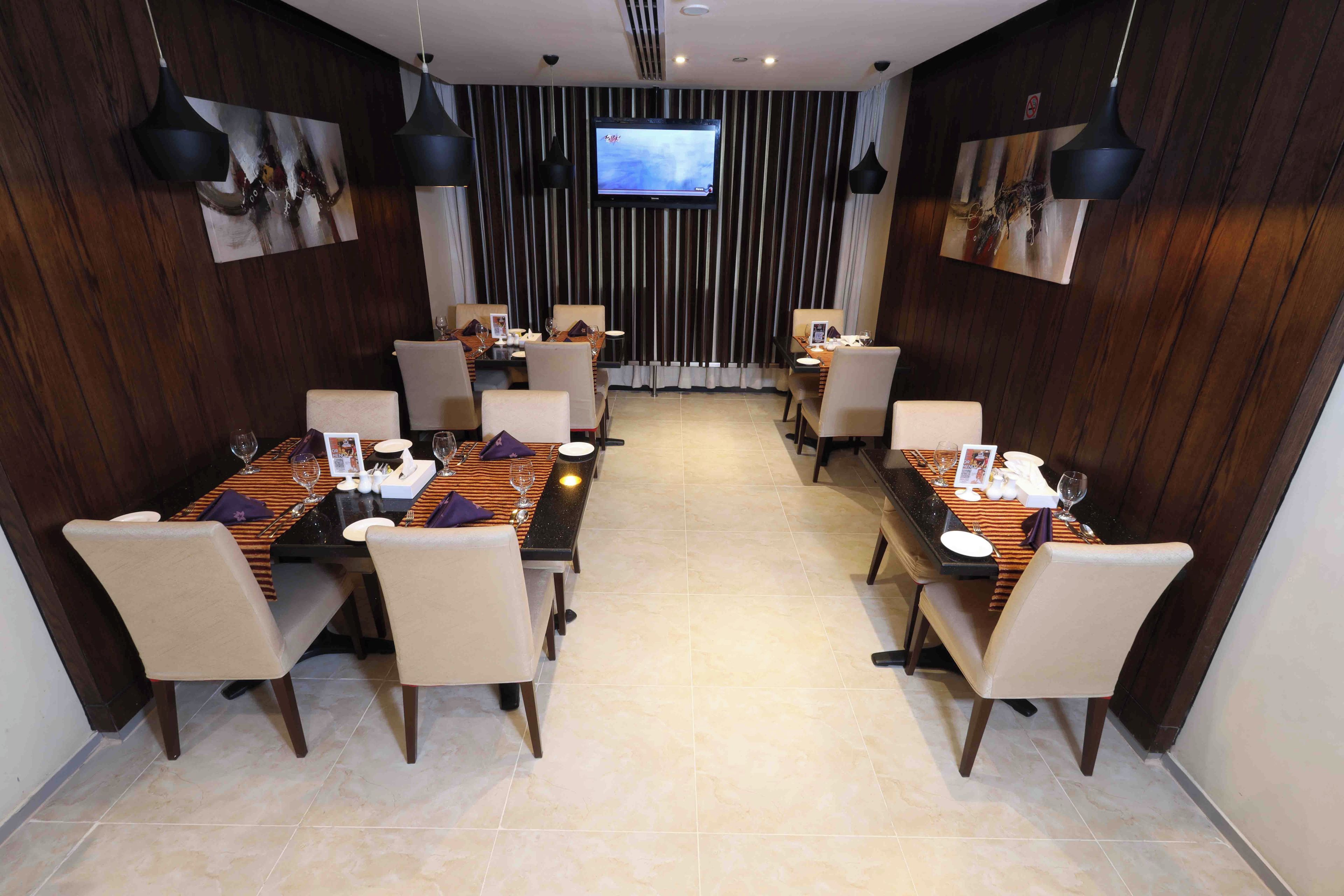 A conference room with two dining tables, chairs, and a TV screen on the wall.