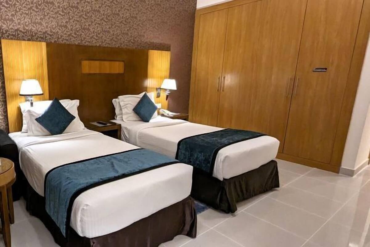 Una habitación de hotel con dos camas, un armario y una mesita.