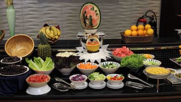 Un bufé con diversos alimentos, entre ellos frutas, verduras y ensaladas.