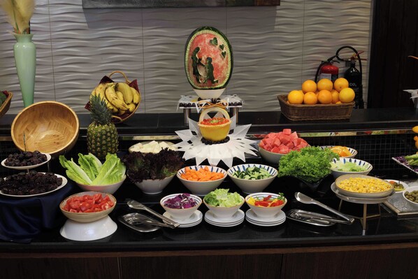 A buffet with various food items including fruits, vegetables, and salads.