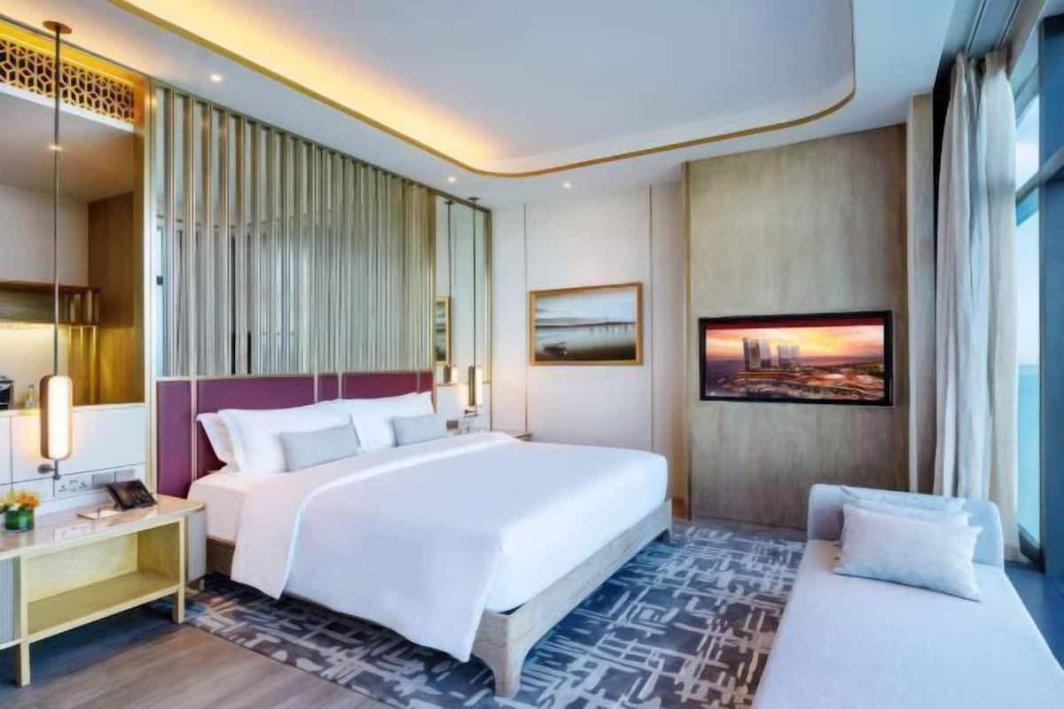 Una habitación de hotel moderna con una cama grande, un sofá, un escritorio y un cuadro con una vista urbana.
