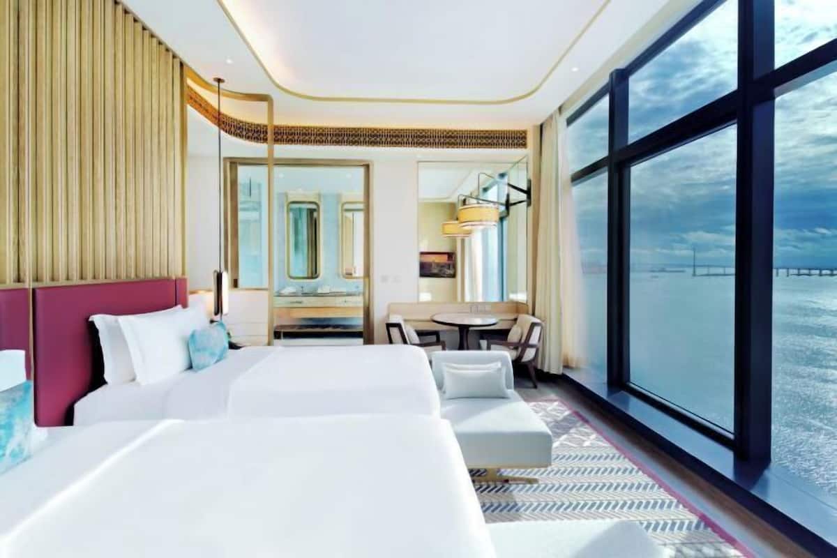 Habitación de hotel con una cama grande, un escritorio y vistas a la ciudad.