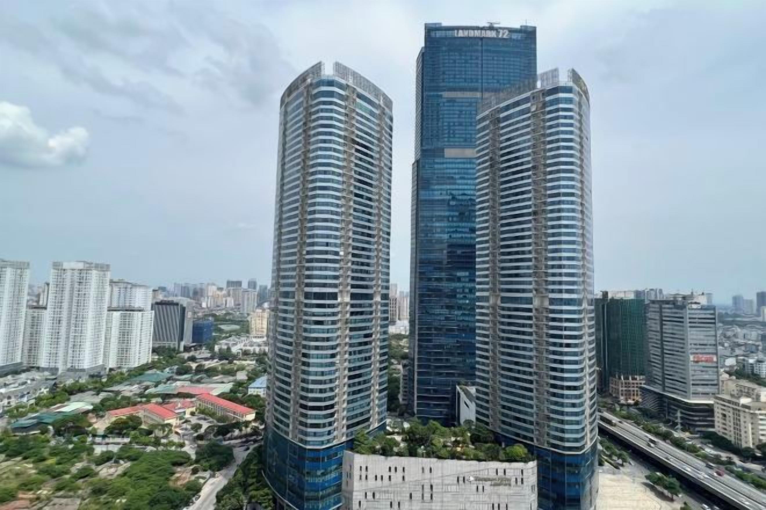 Two high-rise buildings with a clear sky and surrounding urban landscape.