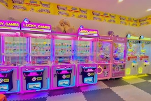 A row of brightly lit claw machines with the 'Lucky Games' logo, arranged in a row on a floor with a checkered pattern.