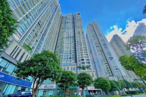 A high-rise building with multiple floors, surrounded by trees and other buildings.