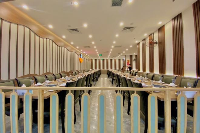 A conference room with a long table, multiple chairs, and a high ceiling with recessed lighting.