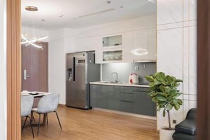 A modern kitchen with stainless steel appliances, a dining area with a table and chairs, and a potted plant.