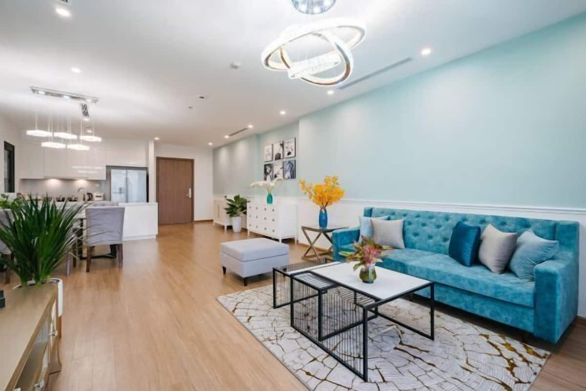 Uma sala de estar moderna com um sofá azul, uma mesa de centro e um espaço de jantar com cadeiras e uma mesa.