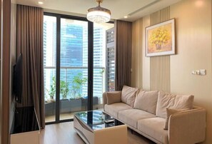 A modern living room with a sofa, a glass coffee table, and a large window with a city view.
