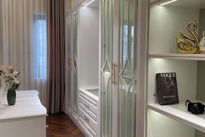 A room with a white vanity, a vase with flowers, a mirror, and a wardrobe with glass doors. - AA Luxury Housing (Hanoi)