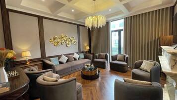 A spacious living room with a sofa set, armchairs, a coffee table, and a chandelier.