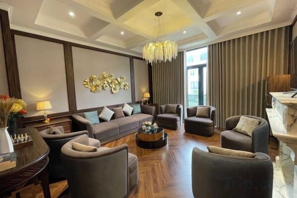 A spacious living room with a sofa set, armchairs, a coffee table, and a chandelier.