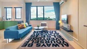 Uma sala de estar moderna com um sofá azul, uma mesinha redonda e uma TV na parede.