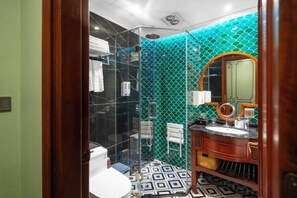 Une salle de bain avec une douche à parois de verre, un lavabo avec un miroir et un carrelage décoratif.