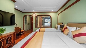 Une chambre d’hôtel avec un grand lit, une télévision, une armoire en bois et une horloge au mur.