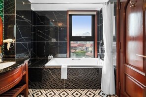 Une salle de bain avec un mur en marbre noir, une baignoire blanche et un sol à motifs.