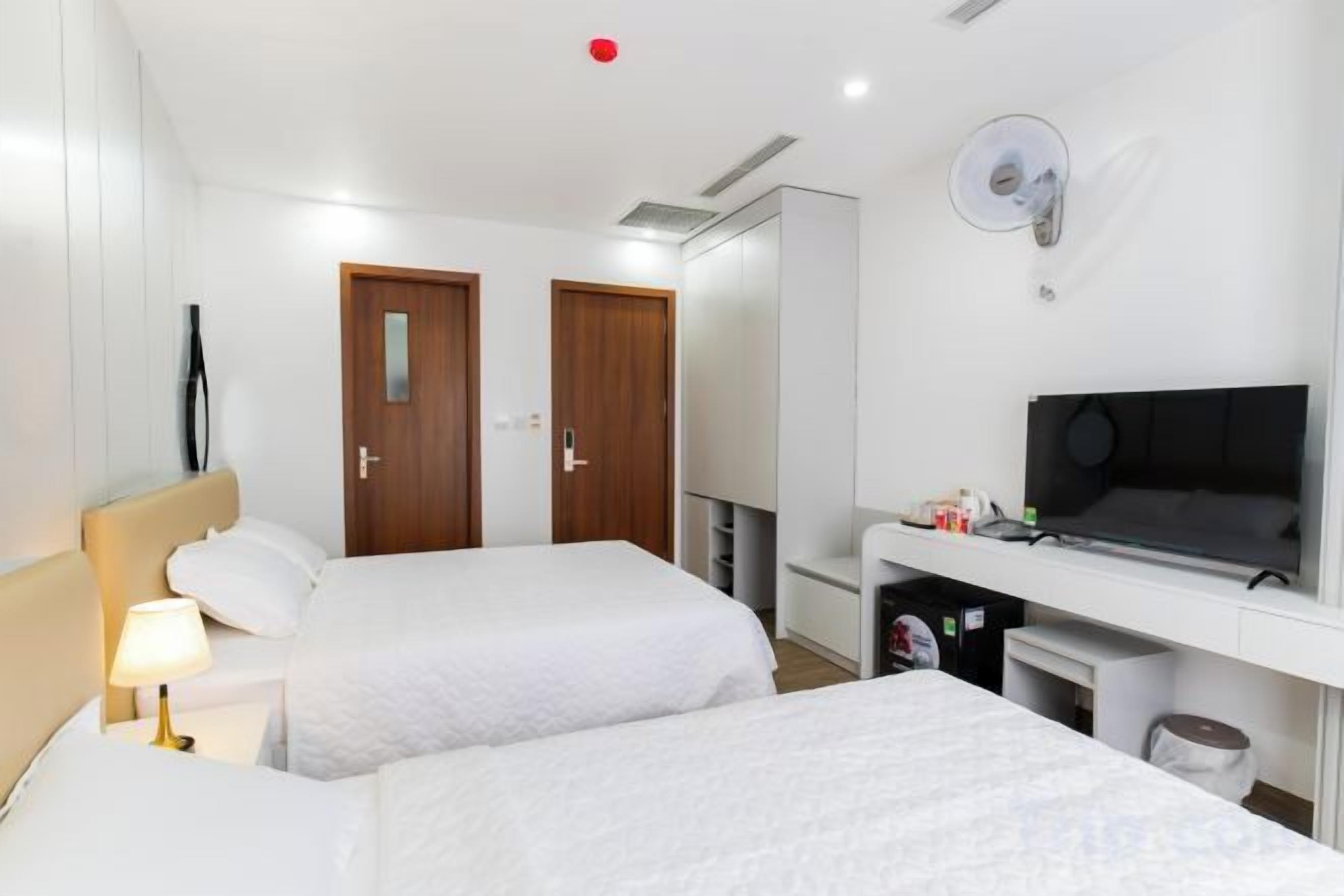 Una habitación de hotel con dos camas, un escritorio, un televisor y un armario.