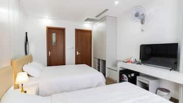 Una habitación de hotel con dos camas, un escritorio, un televisor y un armario.