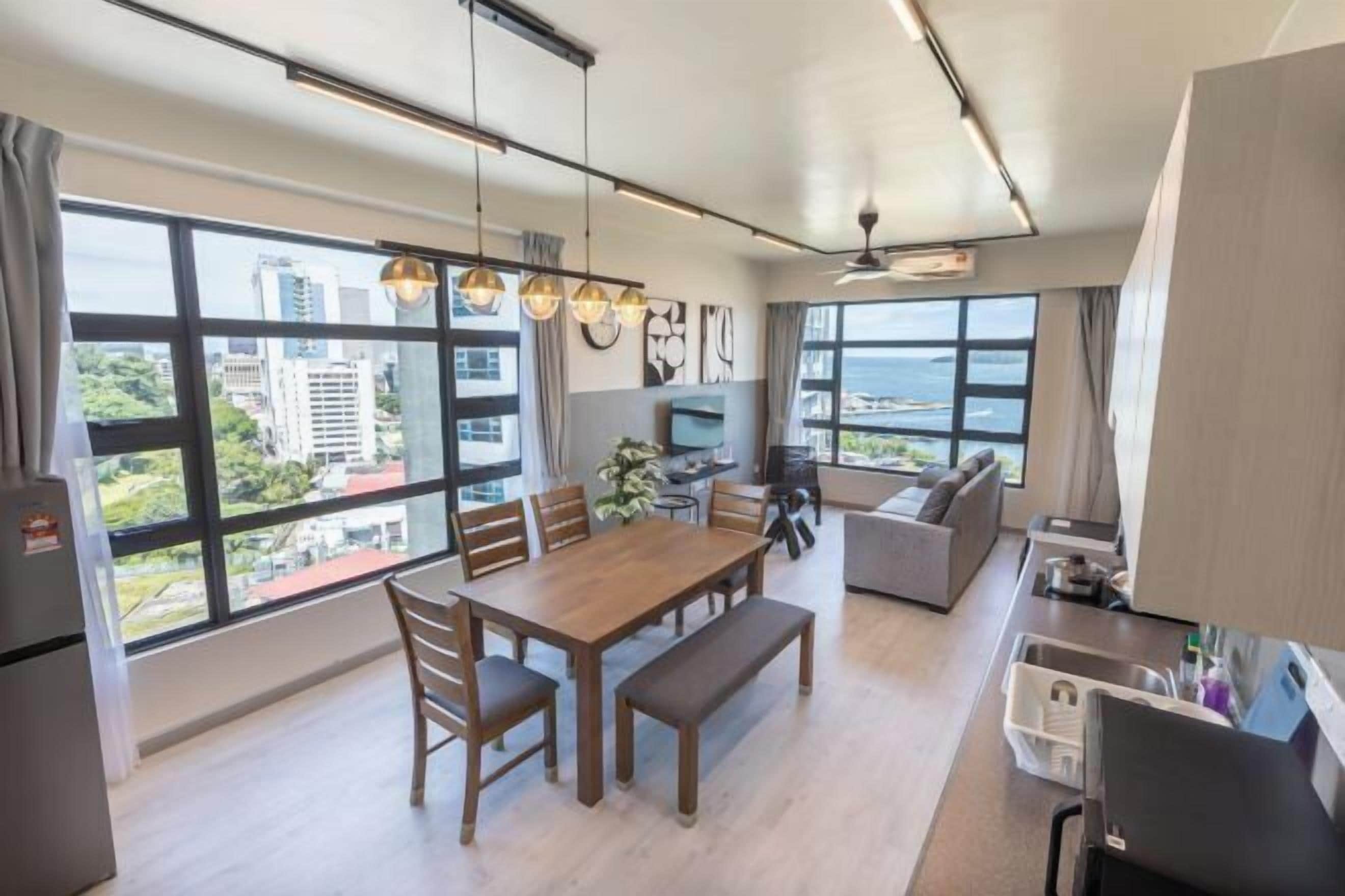 A modern apartment with a dining area, kitchen, and large windows offering city views.