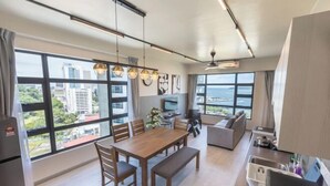 A modern apartment with a dining area, kitchen, and large windows offering city views. - Jesselton Quay Seaview Suite by HayBay (Kota Kinabalu)
