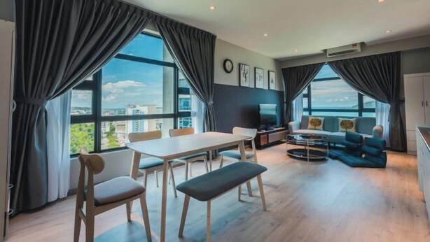 A modern living room with a dining area, large windows, and a view of the city. - Jesselton Quay Seaview Suite by HayBay (Kota Kinabalu)