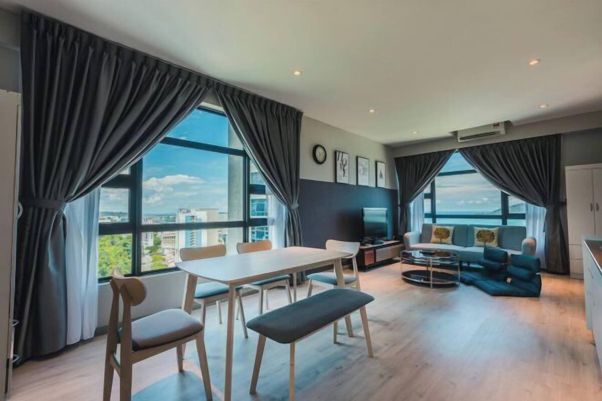 A modern living room with a dining area, large windows, and a view of the city.