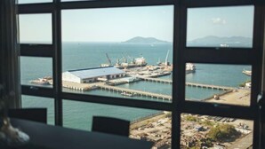 A view through a window of a coastal industrial area with a dock, cranes, and a large building. - Jesselton Quay Seaview Suite by HayBay (Kota Kinabalu)