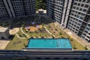 Un área de piscina en la azotea con un espacio de estar circular, rodeada de palmeras y un pequeño jardín.