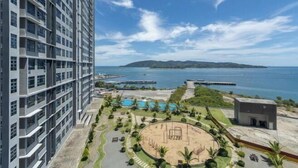 A high-rise building with a swimming pool, a circular park, and a view of the sea. - Jesselton Quay Seaview Suite by HayBay (Kota Kinabalu)