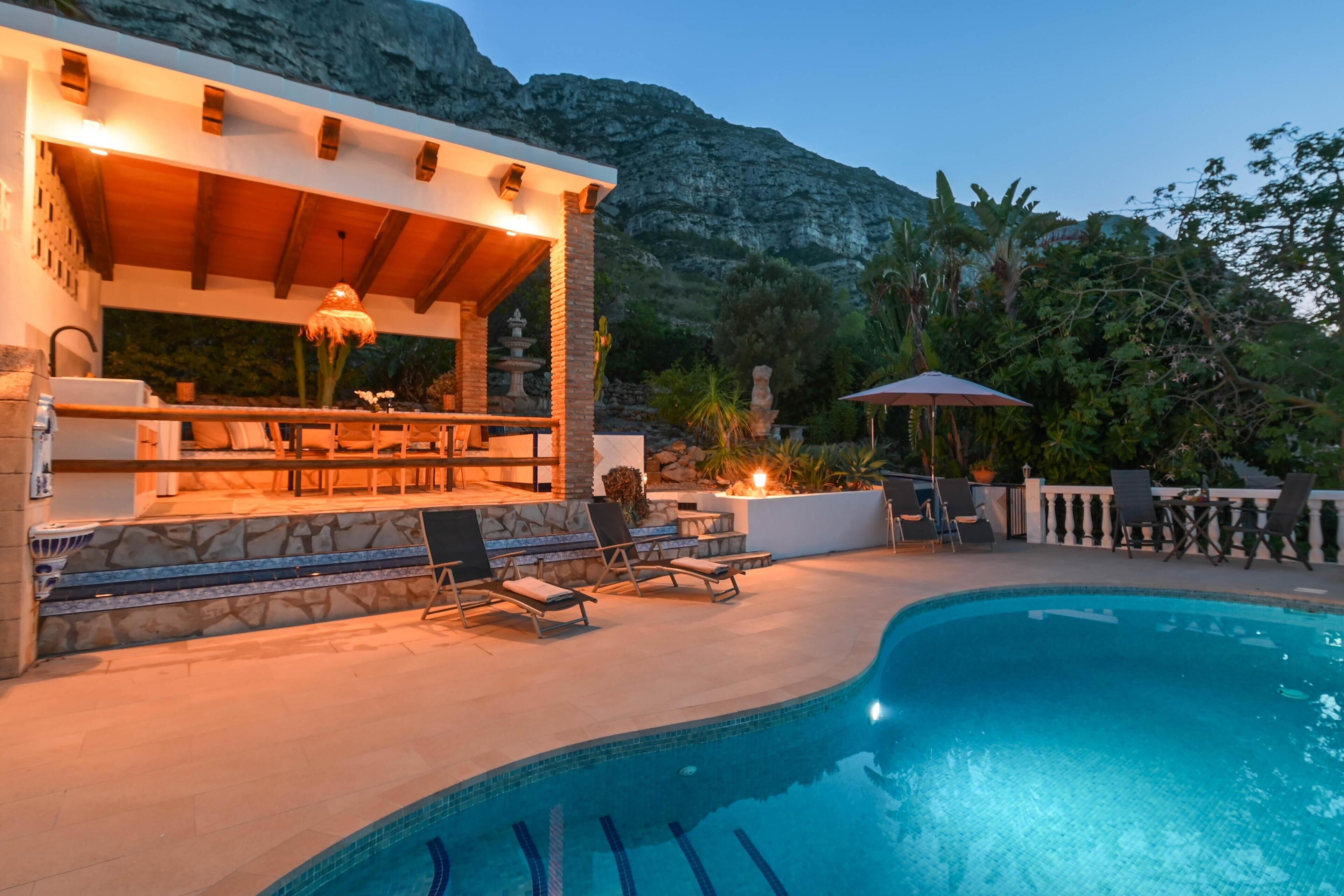 A poolside area with a bar, lounge chairs, and a view of mountains.