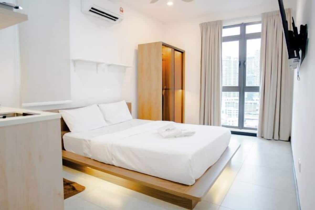 A modern hotel room with a bed, a wardrobe, and a view of the city.
