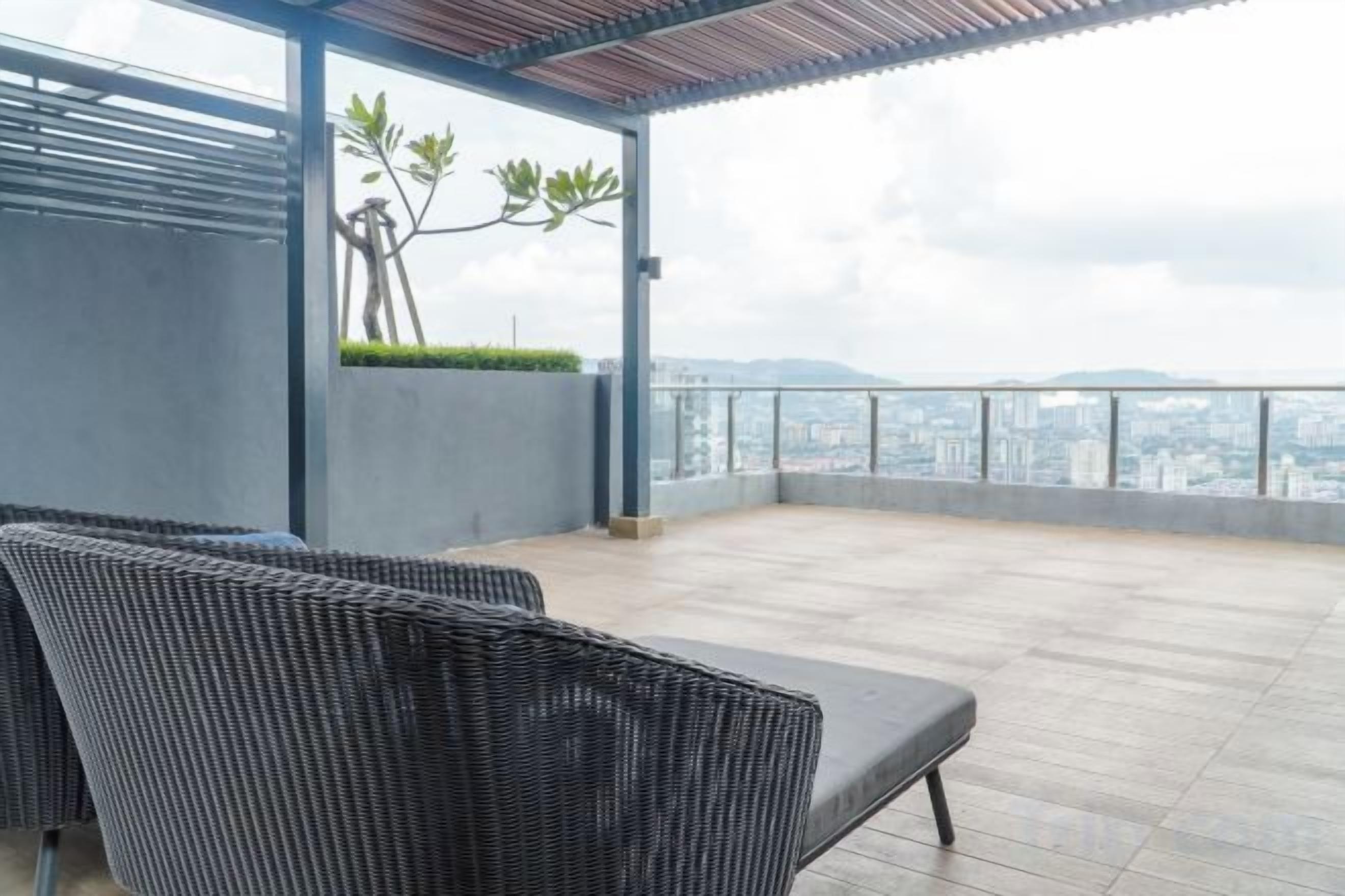 A rooftop terrace with a view of the city, a covered seating area, and a plant.
