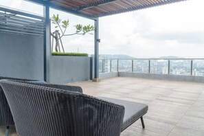 A rooftop terrace with a view of the city, a covered seating area, and a plant.