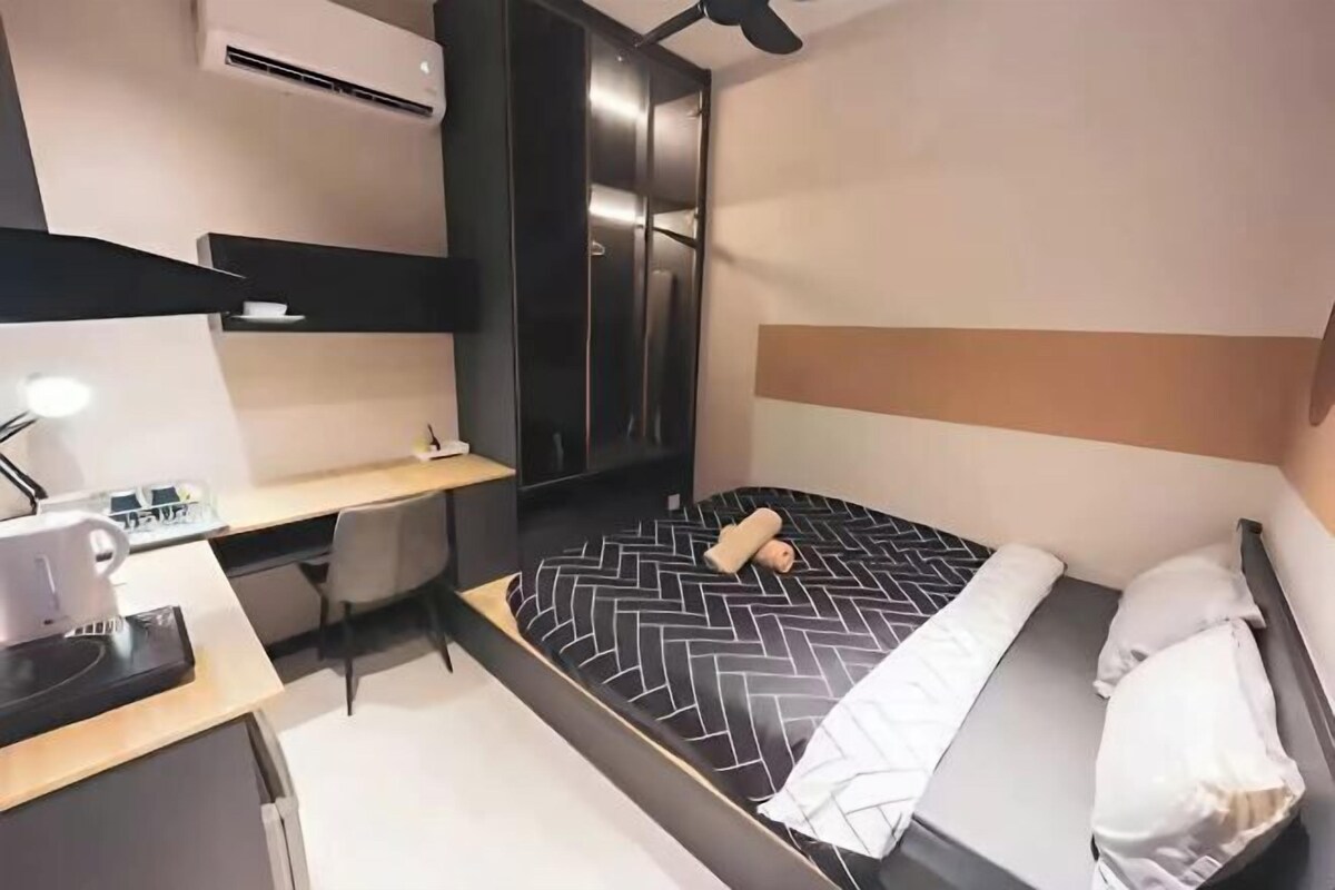 Een moderne hotelkamer met een bed, bureau, stoel en een kledingkast.
