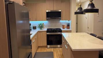 A modern kitchen with wooden cabinets, stainless steel appliances, and pendant lighting.