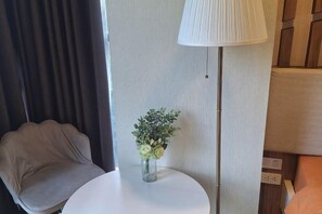 Une pièce comprenant une table ronde, une chaise, une lampe et un vase avec des fleurs.