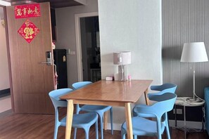 A dining area with a wooden table and blue chairs, a white lamp, and a red decorative hanging on the door. - Dusit Grand Park Resort Apartment Pattaya (Pattaya)