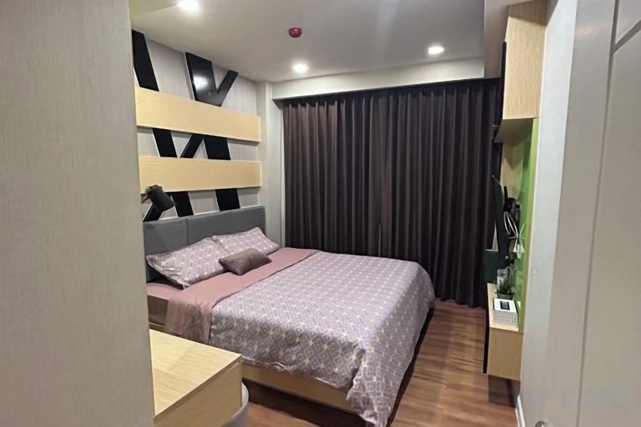 A modern bedroom with a bed, bedside tables, and a curtain.