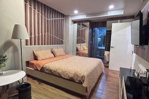 Une chambre à coucher moderne avec un lit, une table de chevet, une lampe et un téléviseur.