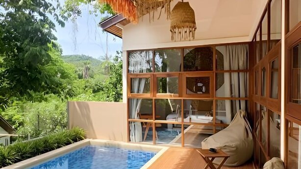 A poolside area with a clear view of lush greenery, a wooden deck, and a large window with curtains. - Villa Lucky, Villa 13 (Koh Samui)