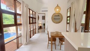 A spacious room with large windows, a wooden dining table, and a view of a swimming pool. - Villa Lucky, Villa 13 (Koh Samui)