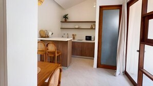 A compact kitchen with a dining area, wooden furniture, and a small island. - Villa Lucky, Villa 13 (Koh Samui)