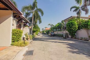 Une rue résidentielle bordée de maisons, de palmiers et de voitures garées.