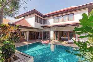 Une maison à deux étages avec une piscine, de grandes fenêtres et un patio couvert.