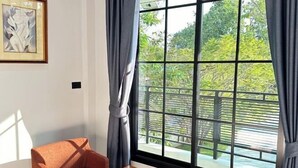 A room with a large window, a framed artwork on the wall, and a wooden table. - Bamboo Resort (Si Prachan)